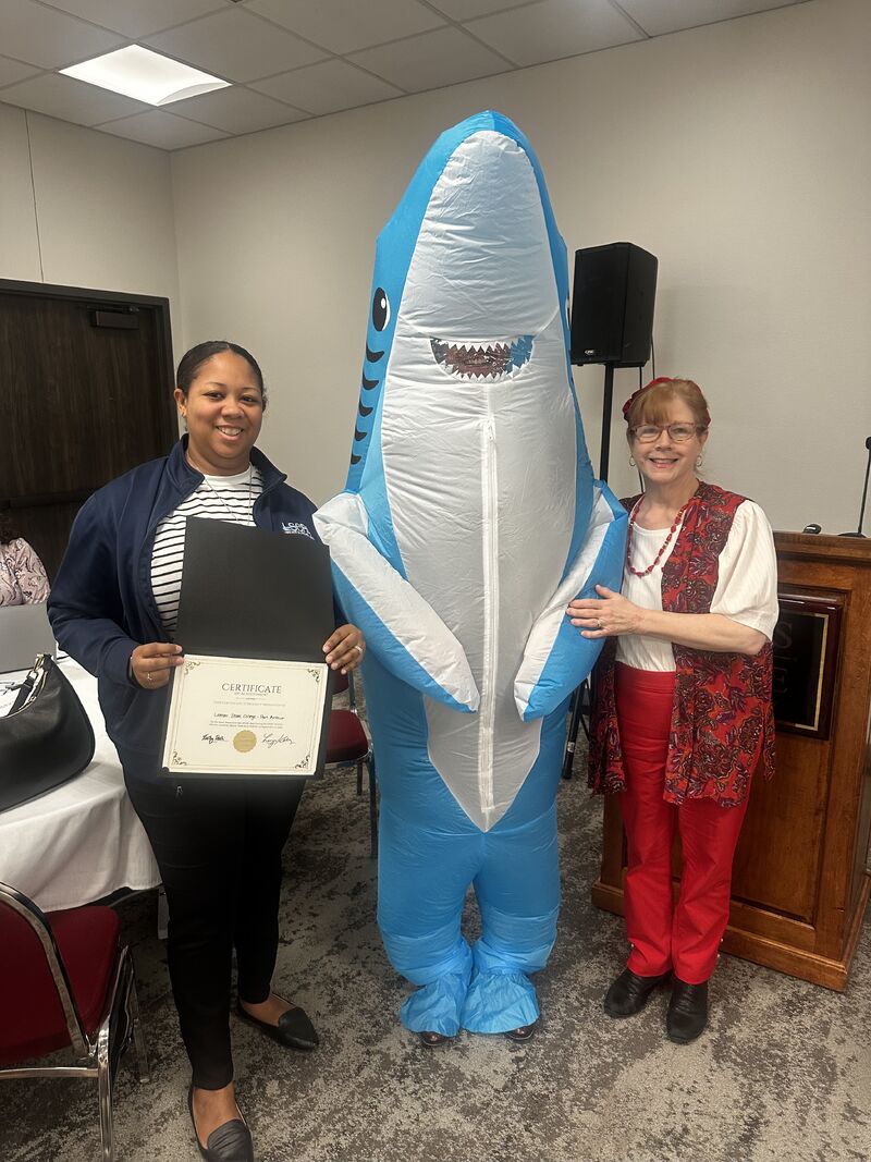 Two women with person in shark costume.