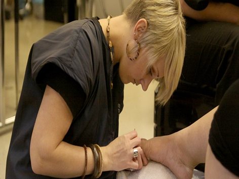 Woman performing a pedicure.