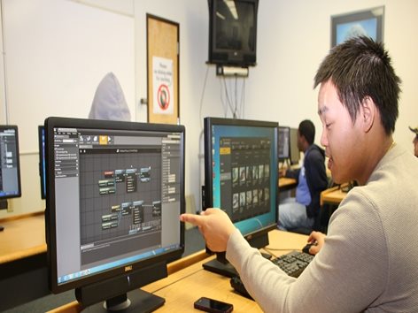 Student working at computer, pointing at monitor.