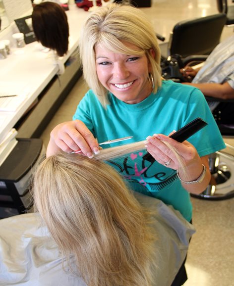 Smiling woman performing a haircut.