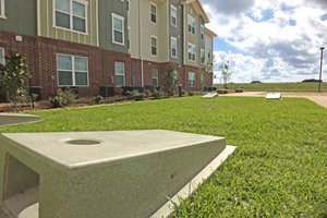 Picture of the building and the lawn with the cornhole game in the foreground.